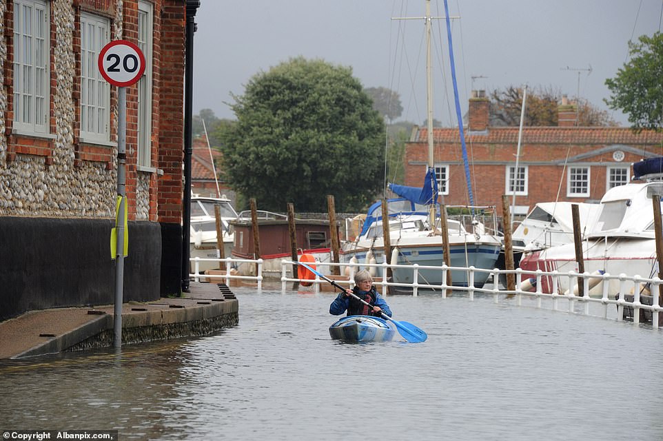 A canoeist paddles down Blakeney High Street past Blakeney Hotel as the water floods over the quay in Norfolk this morning