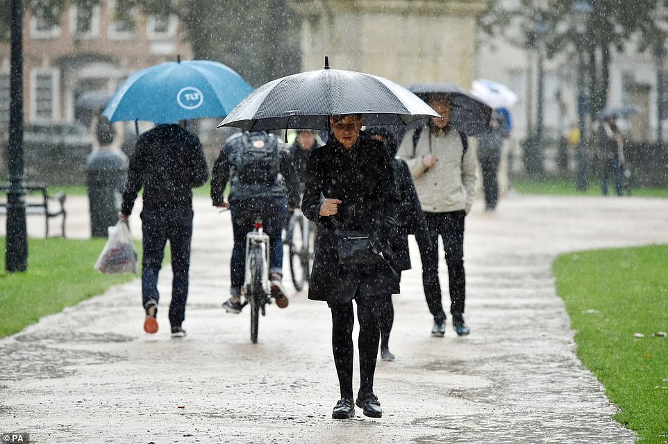 Commuters shelter from the rain under umbrellas at Queen Square in Bristol as the country is hit by torrential rain today